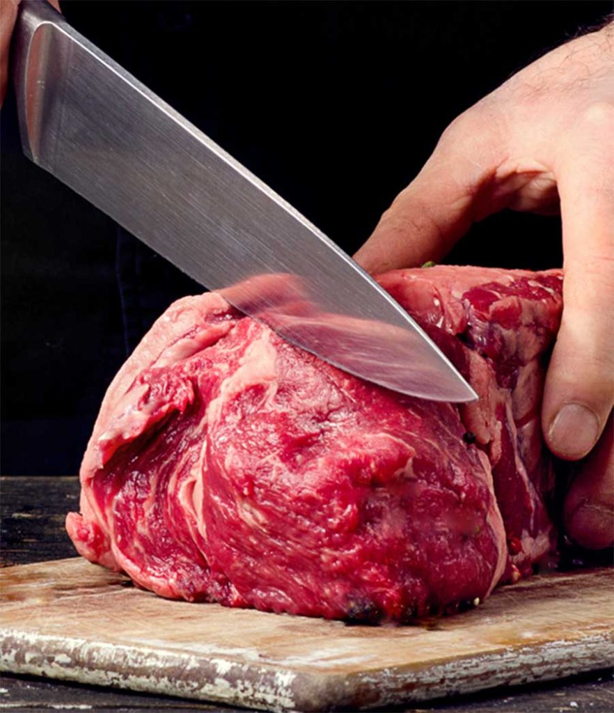 Cortando carne roja sobre una tabla.