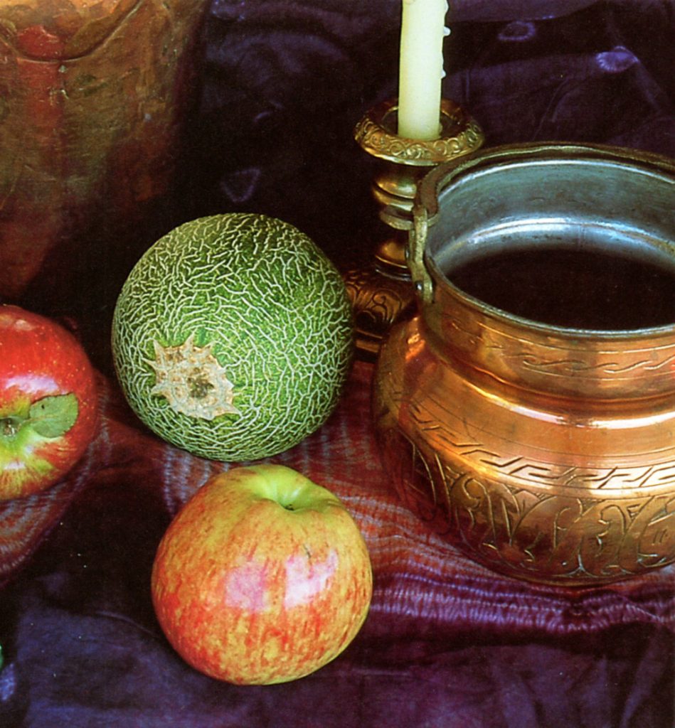 Bodegón andalusí de fruta, caldero de cobre y palmatoria de bronce con vela blanca.