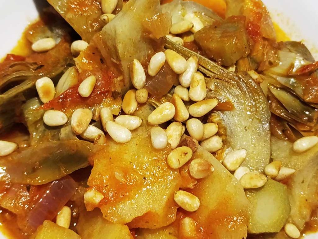 Alcachofas con patatas, tomates y piñones.